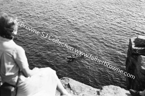 WOMEN SITING ON TOP OF CLIFFS LOOKING AT CURRAGH